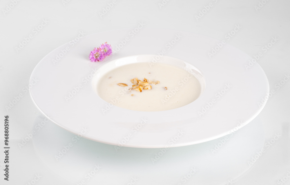 Gourmet mushroom soup in a white bowl, garnished with edible flowers and herbs on a white background. Exquisite presentation. Gourmet mushroom soup in a white bowl, garnished with edible flowers and herbs on a white background. Exquisite presentation.