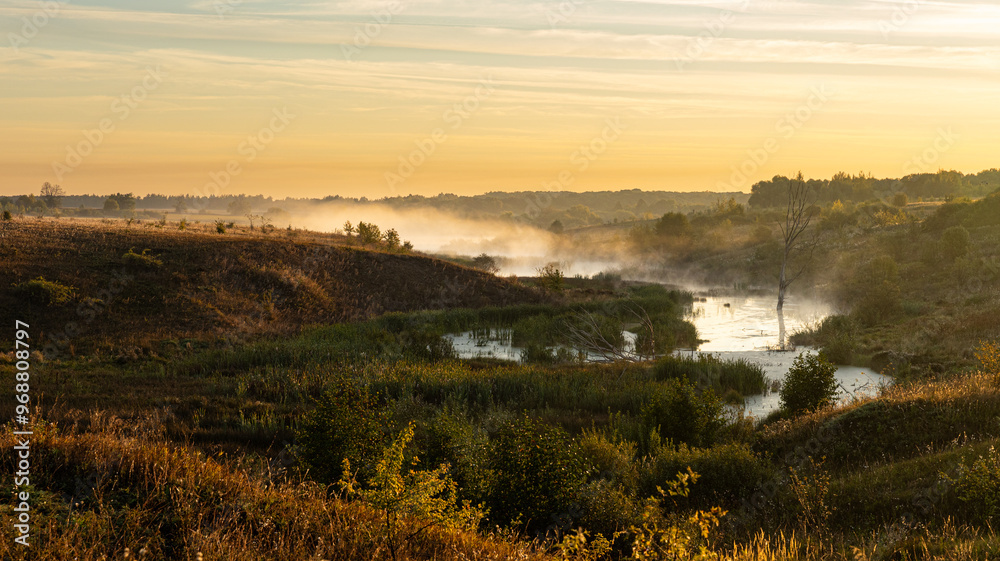 There is a mysterious and foggy landscape featuring a river in the foreground There is a mysterious and foggy landscape featuring a river in the foreground