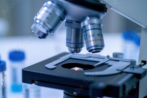 Close-up view of a microscope with glass slide and lens, showcasing precision tools used in laboratory research and medical examination.