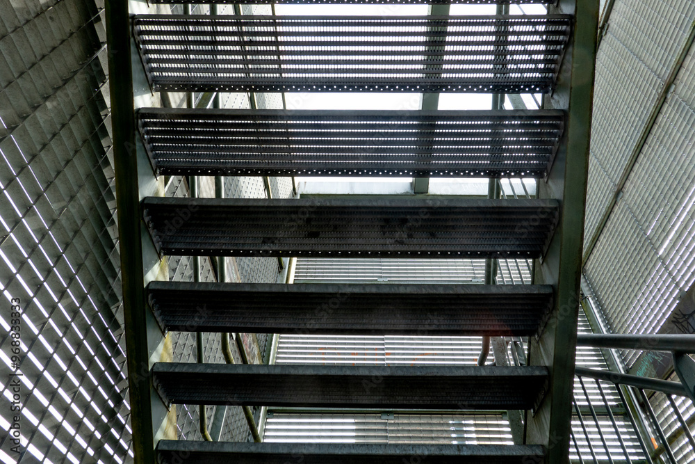 Fototapeta premium Steel staircase leading upward in an industrial building with natural light filtering through