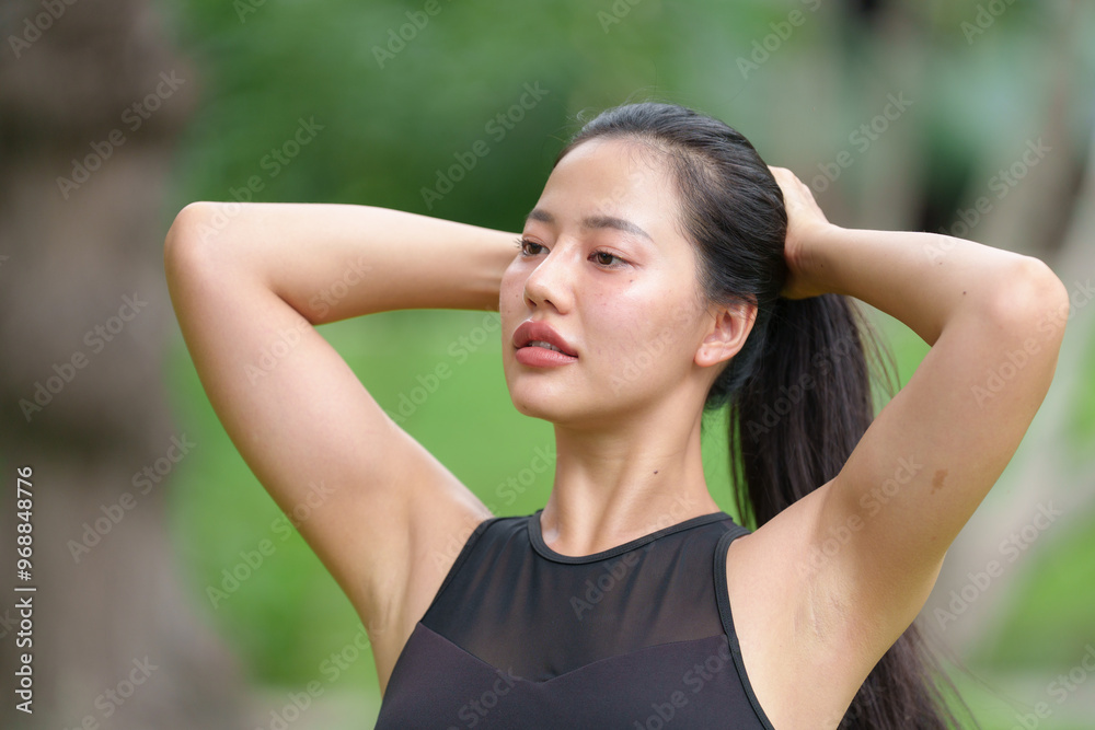 Sporty young Asian woman wearing sportswear is neatly tying her hair before running in a nature park. Sporty young Asian woman wearing sportswear is neatly tying her hair before running in a nature park.