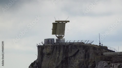 Military radar installation on a rocky mountaintop, surrounded by fencing and antennas. 4K UHD video.