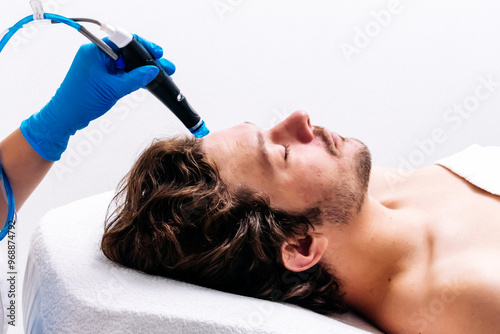 Man undergoing a facial peeling procedure in a beauty clinic, close-up. Rejuvenating hydro-air skin cleansing treatment. Perfect for promoting advanced skincare solutions.