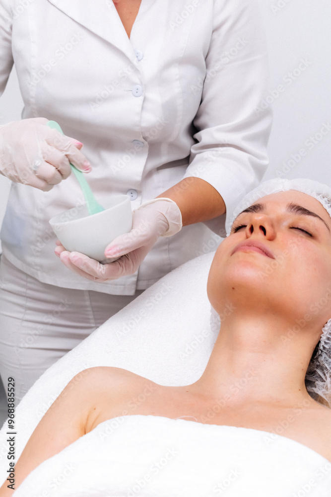 Naklejka premium Young woman wearing an alginate mask in a modern cosmetic center. Perfect for promoting innovative skincare treatments and deep hydration solutions.