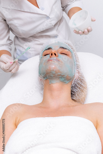 Young woman wearing an alginate mask in a modern cosmetic center. Perfect for promoting innovative skincare treatments and deep hydration solutions. photo