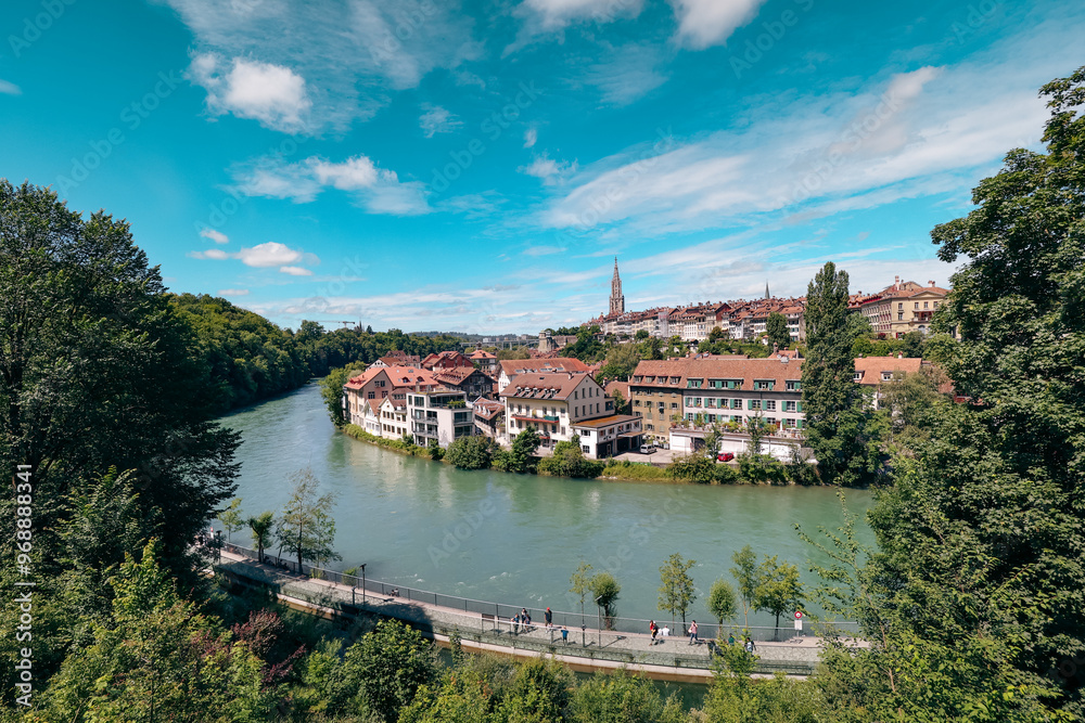 A panoramic view of the Aare River winding through Bern, Switzerland on a bright sunny day with vibrant greenery and historical architecture A panoramic view of the Aare River winding through Bern, Switzerland on a bright sunny day with vibrant greenery and historical architecture