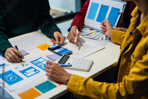 ui designer brainstorming about mobile app interface wireframe design with customer breif and color code at office. photo