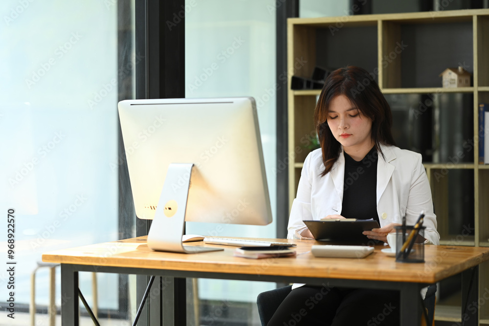 Concentrated young businesswoman analyzing statistics data documents at office desk Concentrated young businesswoman analyzing statistics data documents at office desk