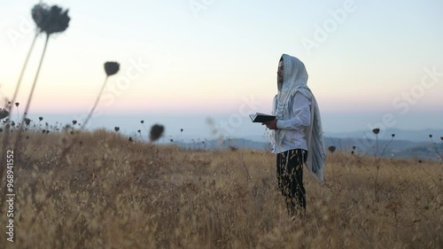 A jew prays in a field at sunrise, with tallit and Sidur. Tfilat Shacharit. photo