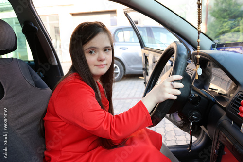 A girl with Down syndrome driving a car.