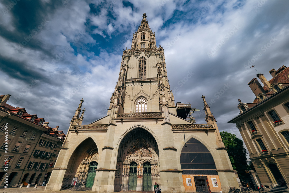 Obraz premium Explore the historic Gothic architecture of Bern’s Cathedral under dramatic cloud formations in Switzerland’s capital city