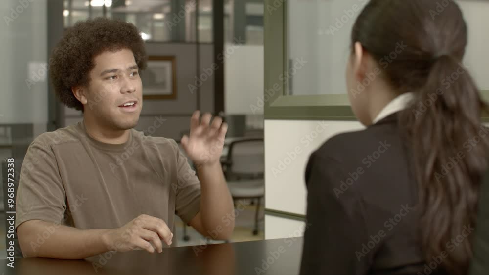 African American male in his 20's with a woman talking in an office setting with stable over the shoulder shot. African American male in his 20's with a woman talking in an office setting with stable over the shoulder shot.
