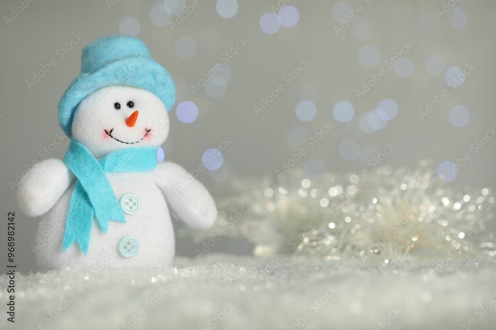 Cute decorative snowman on artificial snow against blurred lights. Space for text Cute decorative snowman on artificial snow against blurred lights. Space for text