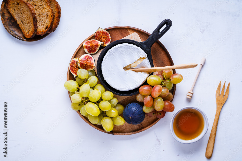 Fototapeta premium Baked camembert cheese in cast iron pan with fresh figs, grapes, and honey