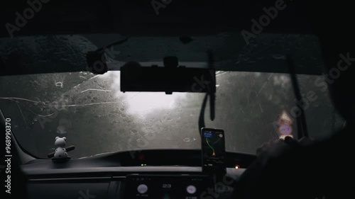 There is a heavy downpour behind the windshield of the car and water flows down the glass. Cool slow motion shots photo