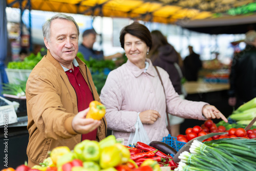 Elderly man and woman buy pepper at an open market