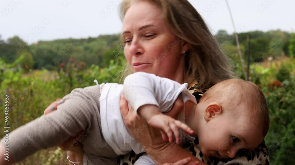 A beautiful grandmother in a leopard suit is holding her little granddaughter in her arms. A young grandmother with her granddaughter outdoors A beautiful grandmother in a leopard suit is holding her little granddaughter in her arms. A young grandmother with her granddaughter outdoors