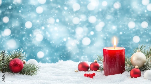Red Christmas candle surrounded by snow, evergreen branches, and red ornaments with snowfall in the background. Cozy holiday decor concept.