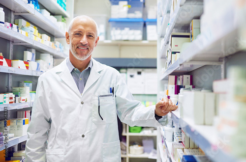 Mature man, pharmacy portrait and inventory check at store, manager and confident chemist. Shop, dispensary and proud of medication treatment at apothecary, expert service and stock shelf in England photo