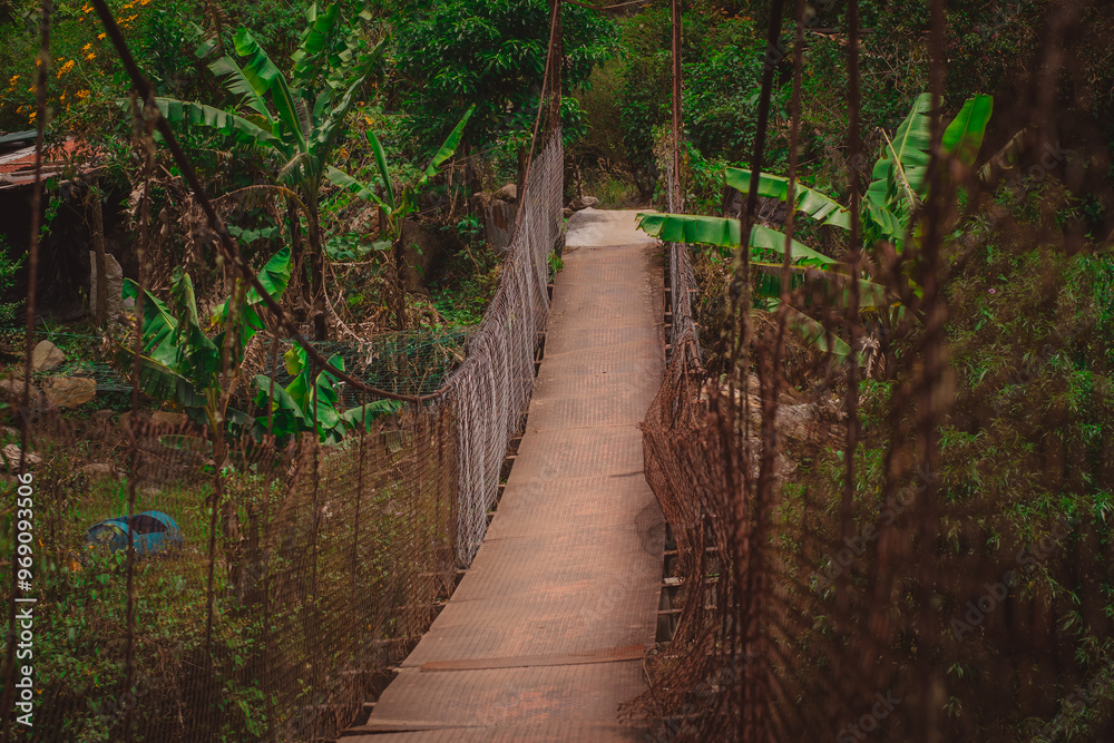 Suspension bridge in poor shape viewed from one side as part of walkways in Bouquete, Panama, in a lush green rainforest or cloudforest. Popular hiking trails in Panama. Suspension bridge in poor shape viewed from one side as part of walkways in Bouquete, Panama, in a lush green rainforest or cloudforest. Popular hiking trails in Panama.