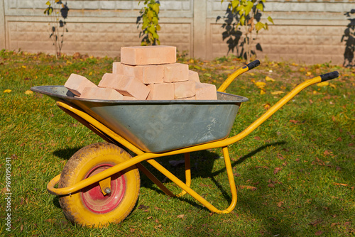 Bricks in Wheelbarrow, a wheelbarrow with bricks stands on the grass on a beautiful autumn day photo