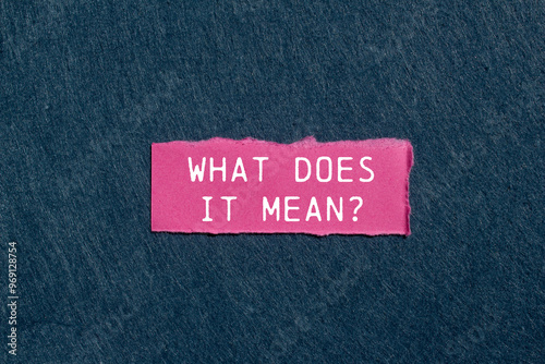 What does it mean question written on ripped pink torn paper piece on gray background. Conceptual what does it mean question symbol. Copy space. photo