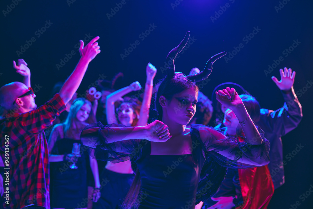 Fototapeta premium Halloween party scene with cheerful young boys and girls, students wearing various costumes, with creepy makeup, cheerful dancing at nightclub. Concept of Halloween, holiday, party, leisure