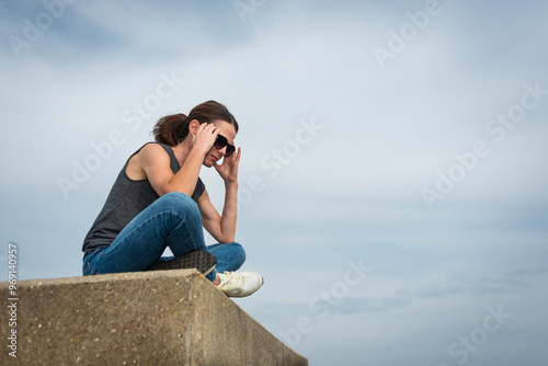 woman sitting outdoors with her head in her hands, depression concept