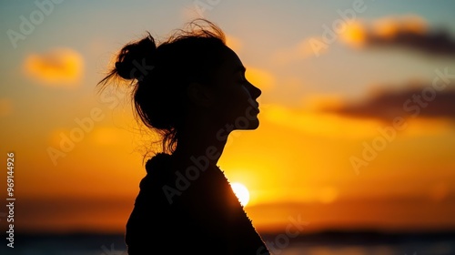 Silhouette of a person against a vibrant sunset by the ocean, evoking tranquility and reflection.
