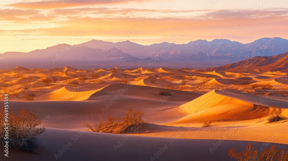 Naklejka premium Serene desert landscape at sunset, showcasing rolling dunes and distant mountains.