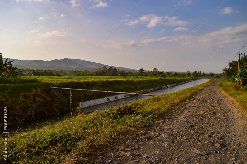 Fototapeta premium The view of the village in the morning. The expanse of rice fields, rivers and also mountains.
