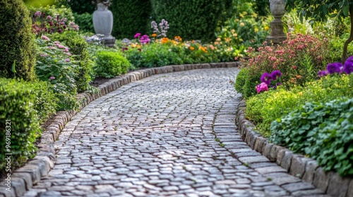 A curved garden path with cobblestones, surrounded by flowering bushes and tall garden sculptures.