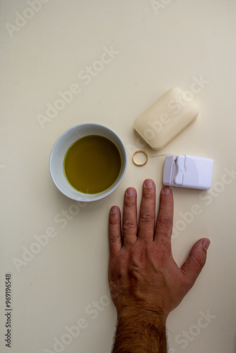 Image of a man's hand and a ring demonstrating products to use when a ring won't come off the finger
 photo