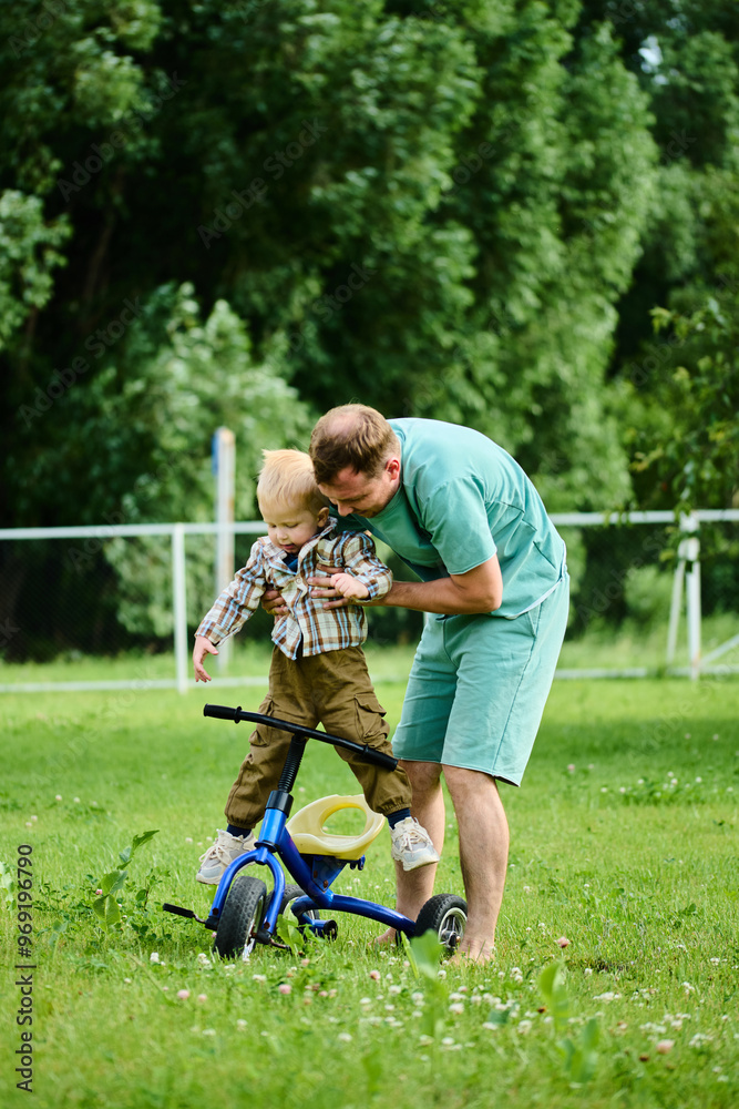 Fototapeta premium Happy family, father teaches little son to ride a bike