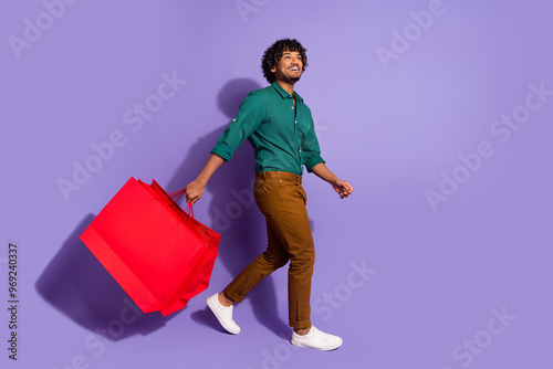 Photo of guy addicted shopaholic with wavy haircut wearing green casual shirt walking in shopping mall isolated on violet color background