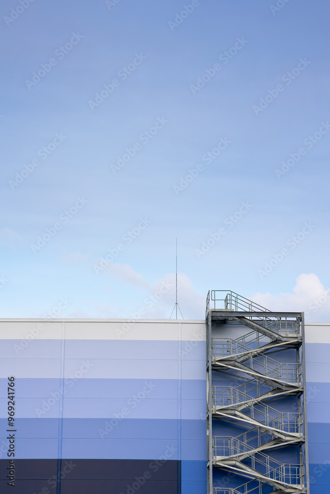 External, evacuation staircase outside the industrial hall made of sandwich panels. Photo taken on a sunny day