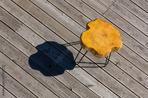 Obraz na płótnie A coffe table made of a light wood trunk against the background of wooden terrace boards. The tree rings of the trunk are clearly visible. A shot of the table from above, taken on a sunny day. w salonie