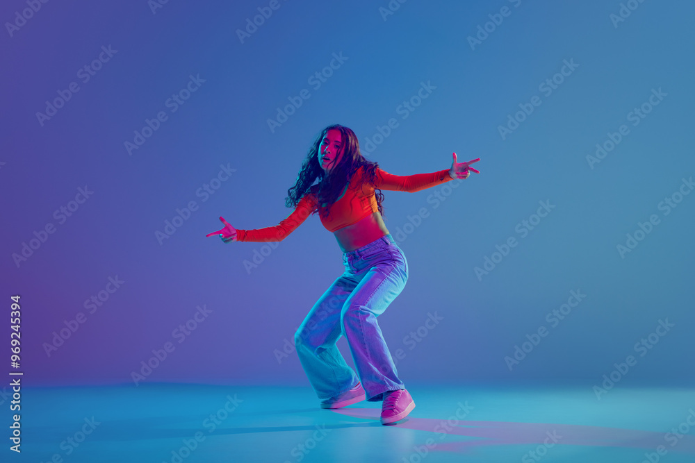 Hip hop training session in full motion, female dancer performing with passion against gradient blue background in neon light. Concept of freestyle dance, modernity, urban culture, youth Hip hop training session in full motion, female dancer performing with passion against gradient blue background in neon light. Concept of freestyle dance, modernity, urban culture, youth