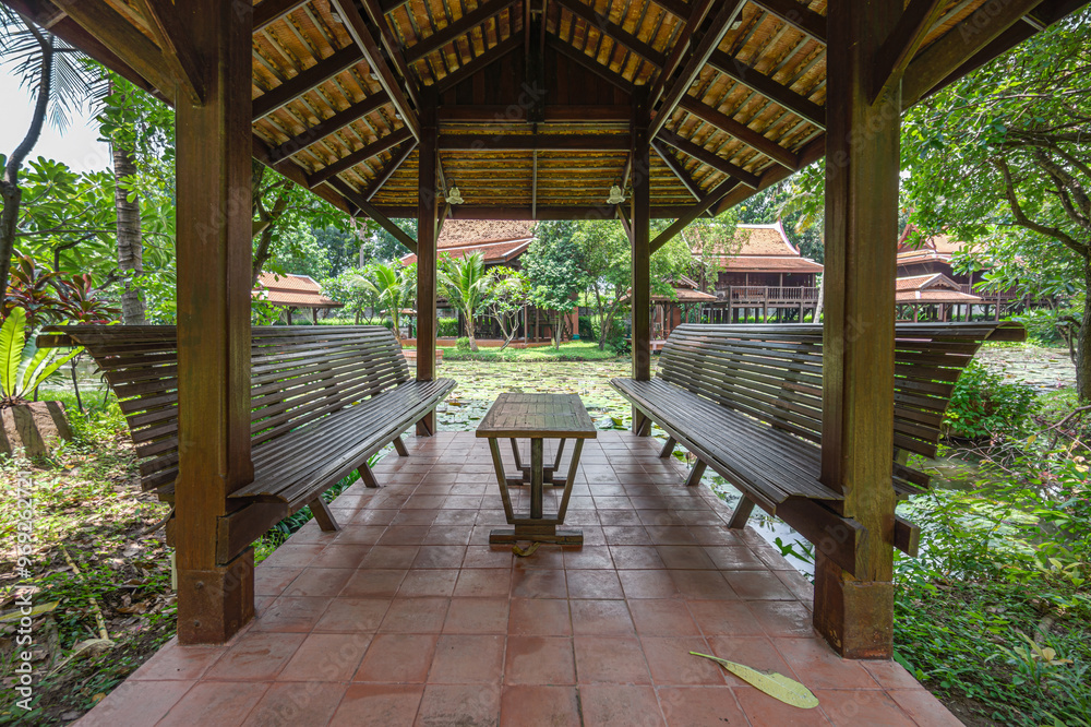 Close-up of an ancient Thai-style pavilion in the garden. It has a long seating area for relaxing and is built entirely of wood and brick block. Close-up of an ancient Thai-style pavilion in the garden. It has a long seating area for relaxing and is built entirely of wood and brick block.