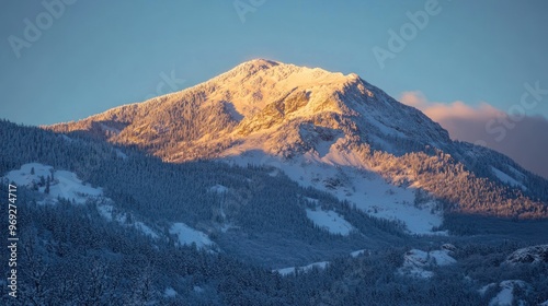 A majestic snow-covered mountain basking in warm sunlight during a serene winter evening.