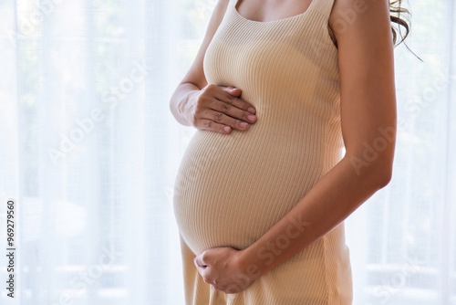 Billede på lærred Pregnant woman standing with her hands gently rubbing her belly, showing love, w