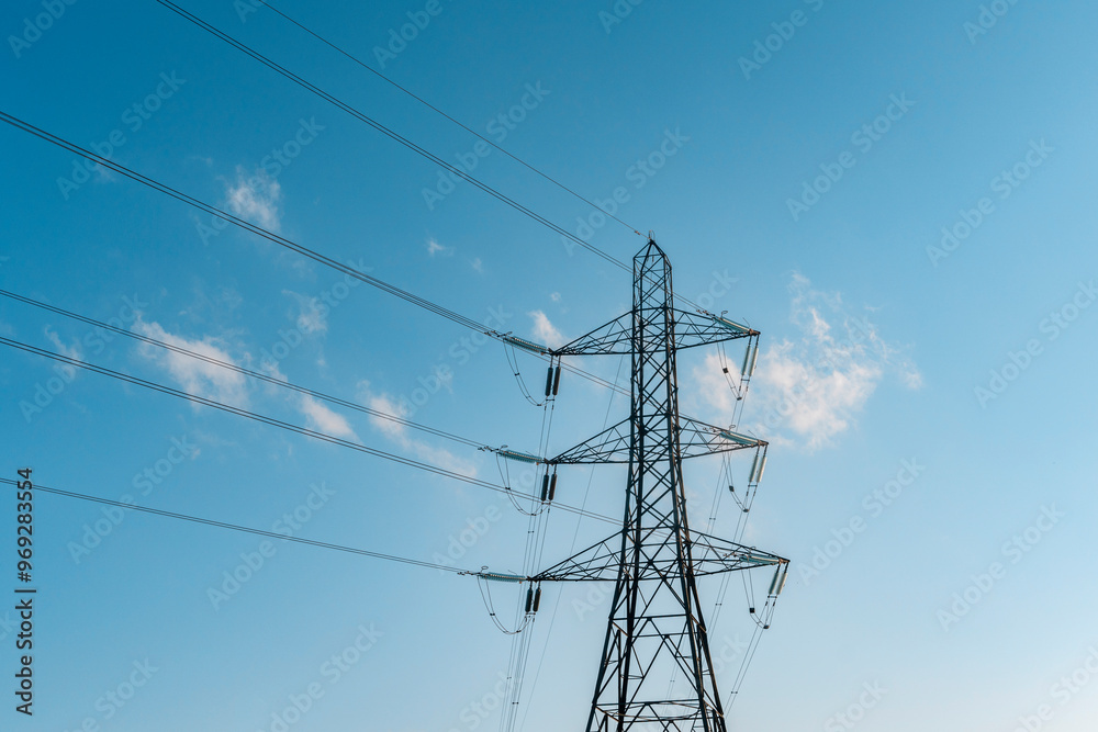 Towering Power Lines Stretch Against a Clear Blue Sky During a Bright Afternoon Towering Power Lines Stretch Against a Clear Blue Sky During a Bright Afternoon