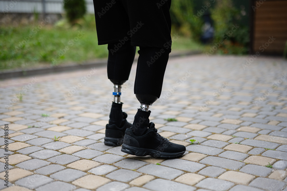 Person with prosthetic legs standing on paved pathway outdoors Person with prosthetic legs standing on paved pathway outdoors