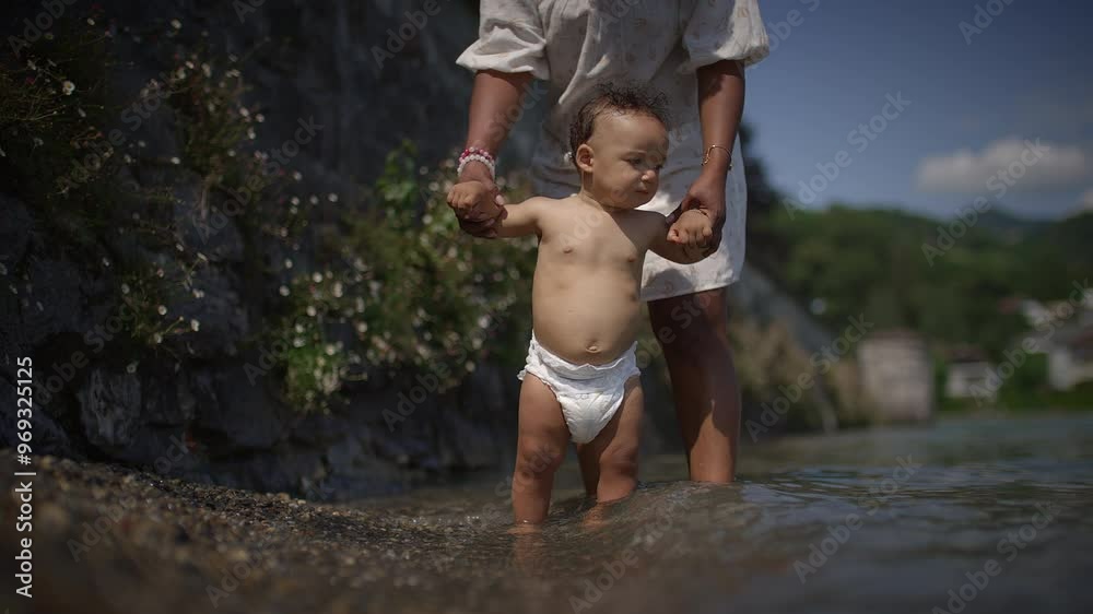 A baby joyfully walks in shallow water with a caring parent, creating precious memories A baby joyfully walks in shallow water with a caring parent, creating precious memories