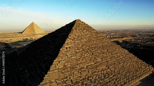 Drone pullout over the pyramids of Giza on a sunny day with clear sky in the background, in Egypt