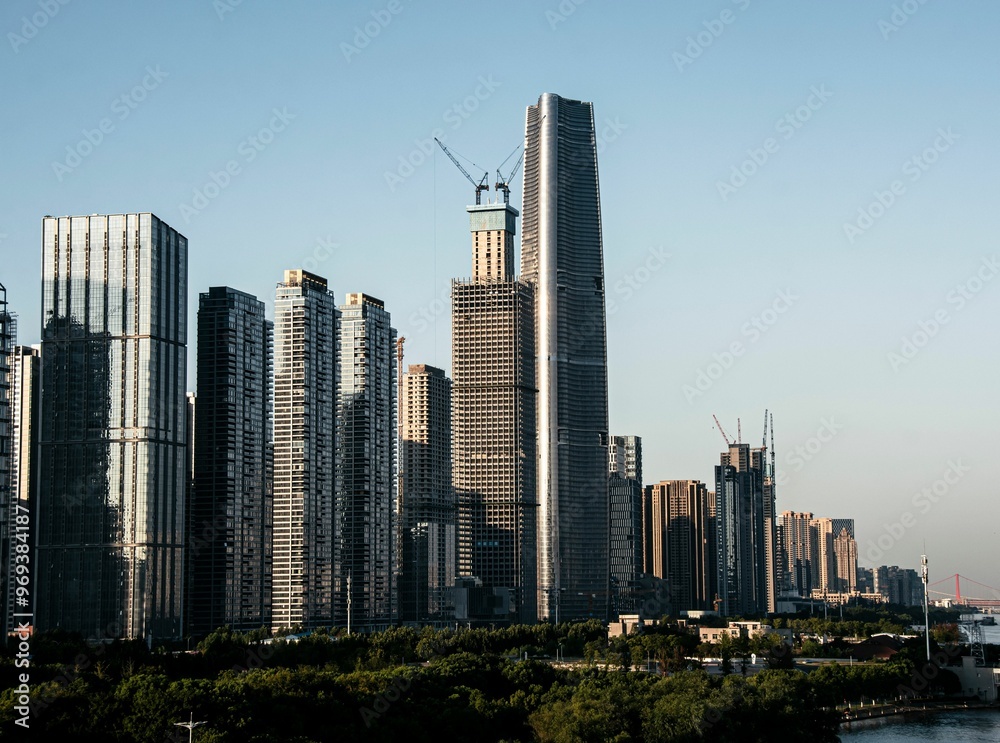 Naklejka premium City skyline with high-rise buildings under construction on a clear day.