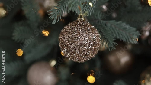 Close up view of beautiful fir branches with shiny silver ball or bauble, xmas ornaments and golden bokeh of garlands light, Christmas holidays background. Decoration on tree. Festive new 2025 year.