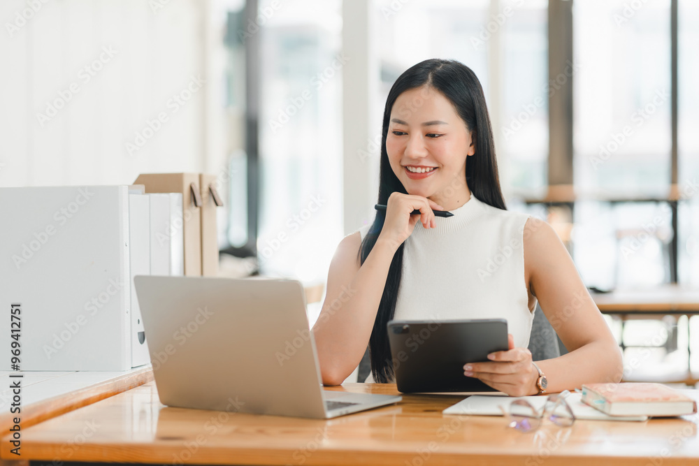 Efficient woman working on laptop and tablet, smiling thoughtfully Efficient woman working on laptop and tablet, smiling thoughtfully