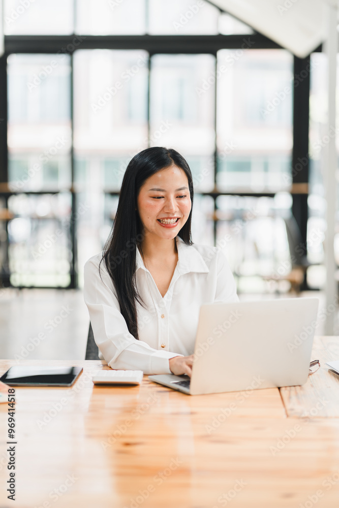 Efficient woman working on laptop in modern office space, smiling happily Efficient woman working on laptop in modern office space, smiling happily