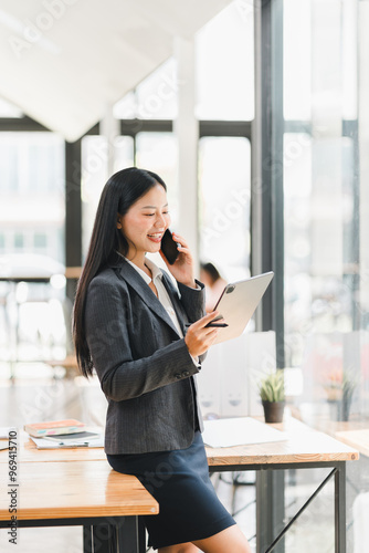 Professional woman in suit using tablet and phone in modern office